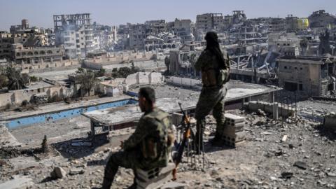 Fighters of the Syrian Democratic Forces stand guard on a rooftop in Raqqa after retaking the city from Islamic State