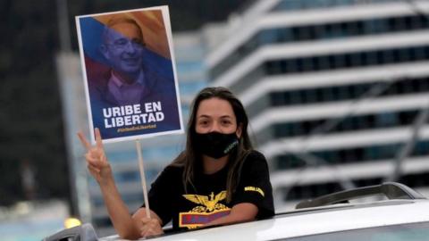 A supporter of Alvaro Uribe, former president and legislator of Colombia, wearing a face mask, holds a sign that reads "Uribe in freedom" during a protest against the house arrest measure ordered by the Supreme Court of Justice, against the former president in Bogota, Colombia August 7, 2020.