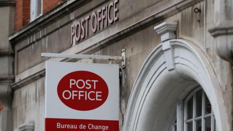 A post office sign hangs above a shop in Belgravia, in London