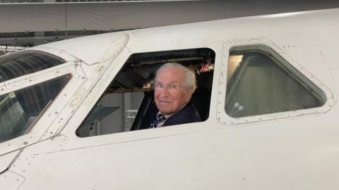 Colin Morris sitting in the cockpit of the retired Concorde looking out the window.