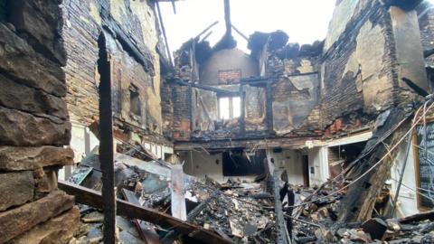 Rubble inside the badly burned remains of a partially collapsed building