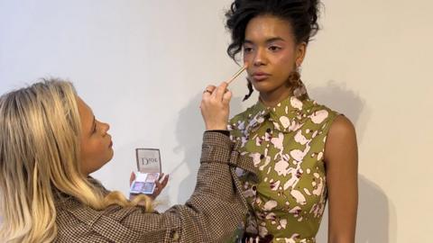 A woman doing the make-up of a model.