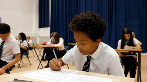 school student sits an exam in a spacious school hall.