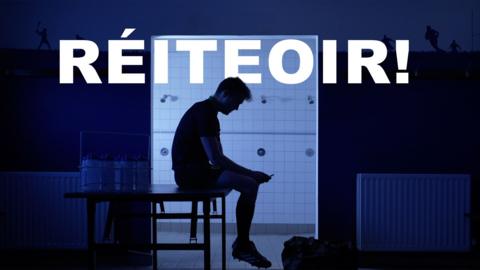 The silhouette of a gaelic football referee sits in an unlit changing room with his head slouched looking disappointed