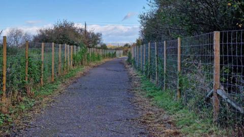 Paved path with fencing either side