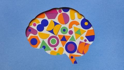 Paper craft illustration of a brain filled with multi coloured geometric shapes.