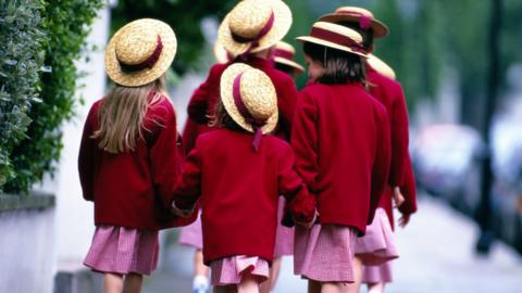 Red uniform private school pupils walk down road