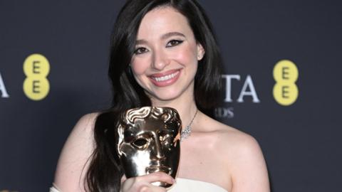 Mikey Madison smiling and holding her Bafta