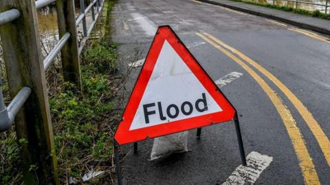 A flood warning sign near to an area of flooding