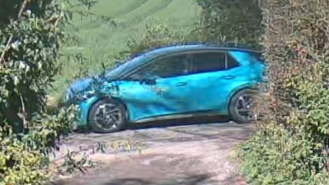 A blurry image of a blue car on a rural road