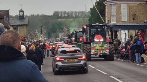 Cars and tractors travelling on a village road