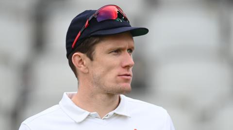 Will Williams looking to the right while wearing a cap and sunglasses on top during a County Championship match for Lancashire last season