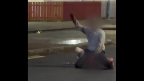 A image of a man with his hand up in the air. His face is blurred. 