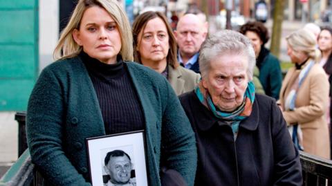 The family of murdered GAA official Sean Brown, daughter Clare Loughran (left) and widow Bridie Brown (right) arriving at Belfast High Court. The daughter is in a dark green cardigan and the widow in a dark coloured trench coat and blue scarf. 