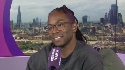 TV presenter Nigel Clarke sits in front of a purple Radio London branded microphone in a studio.