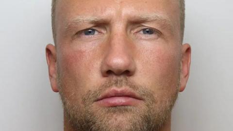 Mugshot of man with short hair and beard