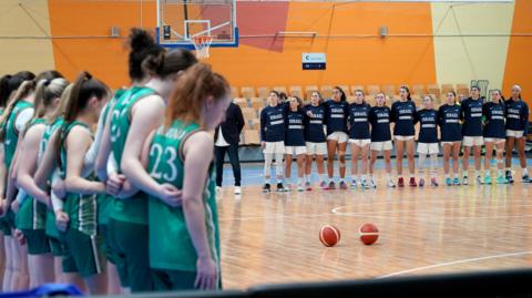Ireland players stand to the side of the court for the national anthems
