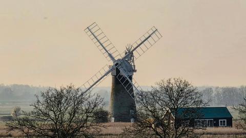 windmill in a field with pink sky behind