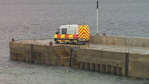 An Irish Coast Guard van parked on a pier surrounded by water