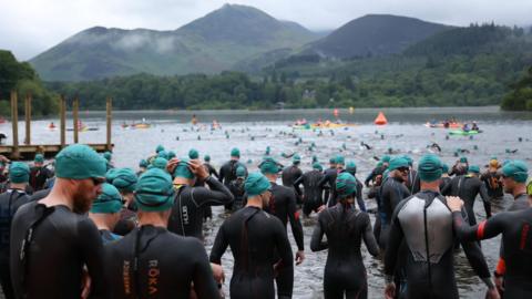 Lots of people getting into water wearing wetsuits.