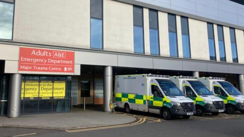 Entrance to the A&E department at Glasgow Queen Elizabeth University hospital, with three ambulances parked up outside. 