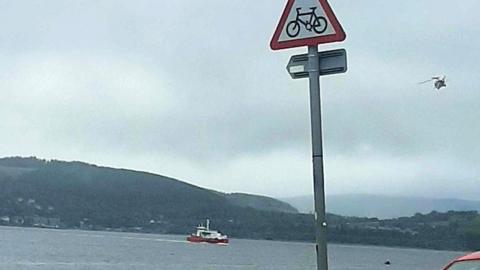 A ferry on the River Clyde as a search operation is launched for a person overboard. A helicopter can be seen in the sky above