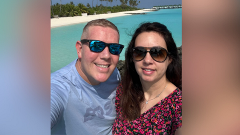 Two people smiling in front of water