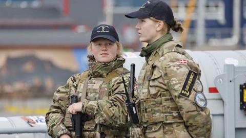 Two female members of the Royal Danish Navy stand guard on a warship in Nuuk, Greenland.