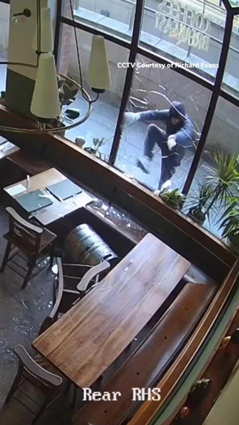 CCTV footage from inside a cafe shows a man climbing inside after breaking the window