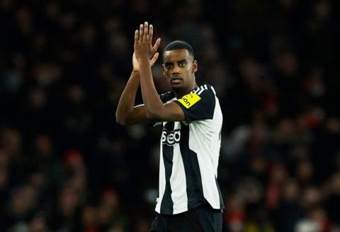 Alexander Isak, pictured during a football match wearing a black-and-white Newcastle United strip, clapping his hands together.