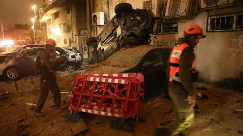 Israeli security checks the damage to cars after a rocket strike in Holon, Israel.