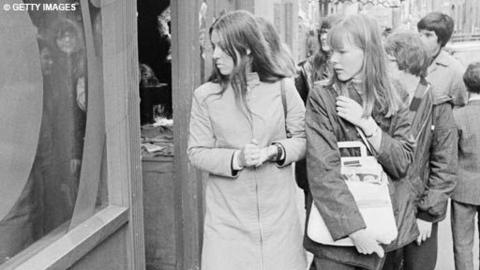 Two teenage girls look at a shop window