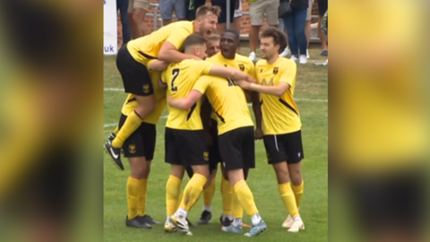 Tadley Calleva players celebrate after the fourth goal against Weymouth at their home ground on Saturday. They are wearing yellow shirts and socks and black shorts.