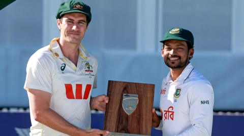 Australia captain Pat Cummins and Bangladesh skipper Nazmul Hossain Shanto hold the trophy after the Test series is tied