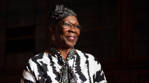 A woman in glasses and a blike and white top