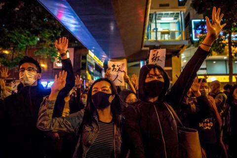 People chant slogans near a police-cordoned-area to show support for a small group of protesters 