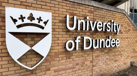 A sign saying University of Dundee attached to a brick wall