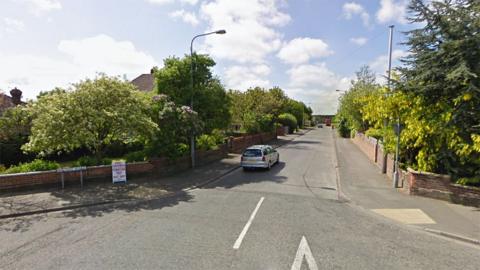 Entrance to Wilton Road in Humberston showing the street sign the road is lined with houses and trees on both side