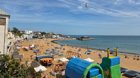 Top shot of crowds on a sandy beach in Broadstairs, Kent, with the sea in the background on a sunny day 