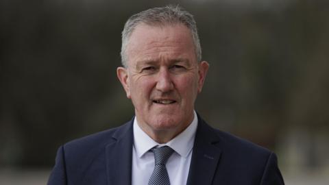 Conor Murphy in dark suit, white shirt and blue tie