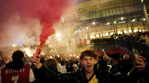 Arsenal fans celebrate outside Emirates stadium after the Gunners won the Premier League