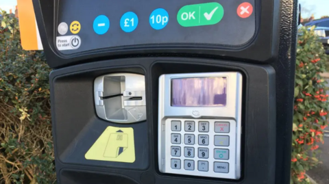 A close-up of a pay and display machine, with a card reader and keypad for people to enter their PIN.