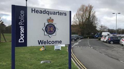 Dorset Police headquarters sign at the entrance to a car park