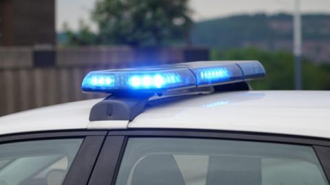 A close-up of a white roof of a police car, with its blue lights on.