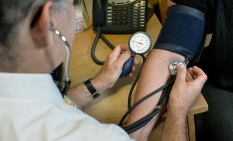 A doctor takes a person's blood pressure.
