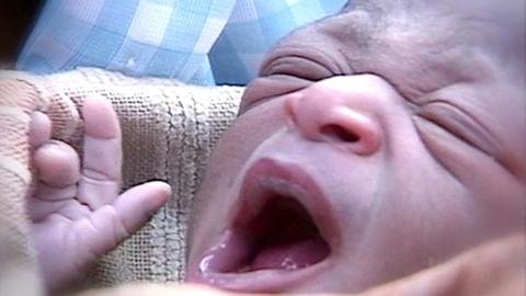 A close-up of a newborn baby yawning.