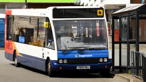 A Stagecoach bus parked next to a bus stop in a street.