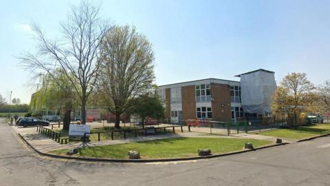 Dorcan Academy entrance with sign and old red-brick, flat-roofed buildings