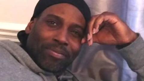 A family photo of Okechukwu Iweha, who is wearing a grey hoodie and is looking at the camera