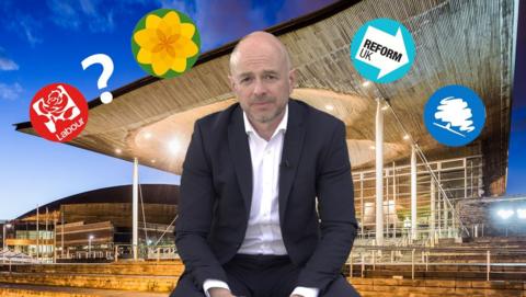 Gareth Lewis sits in front of a background of the Senedd with party political logos superimposed around his head